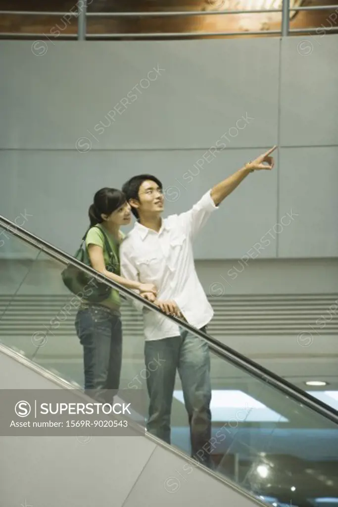 Couple on escalator, man pointing