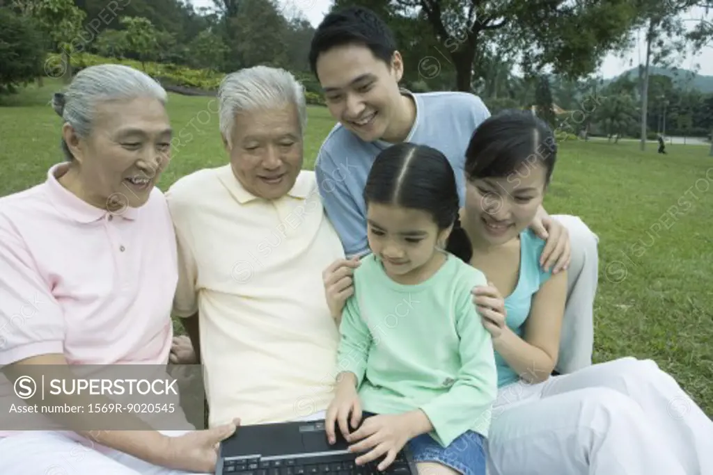 Three generation family, using laptop in park