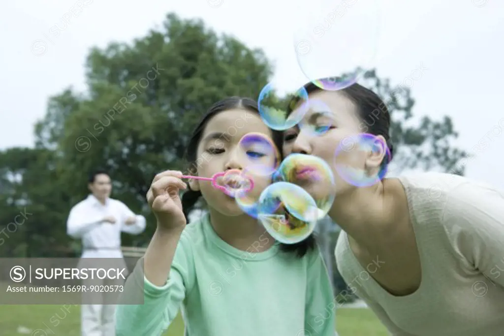 Girl and mother blowing bubbles