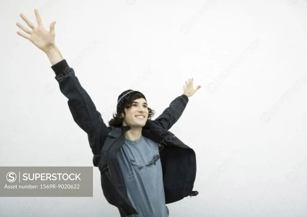 Young man standing with hands up in air