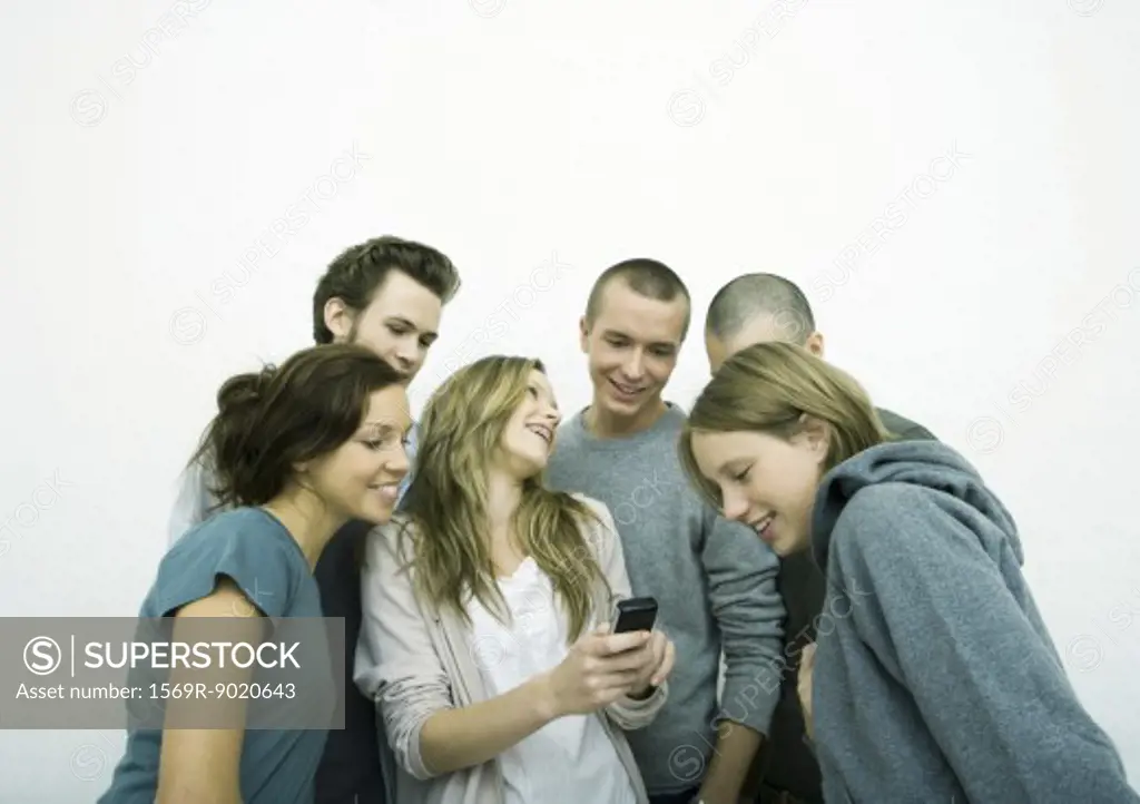 Group of young adult and teenage friends looking at cell phone, white background