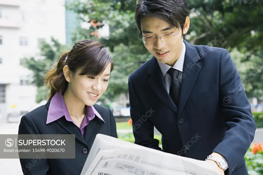 Business couple reading newspaper