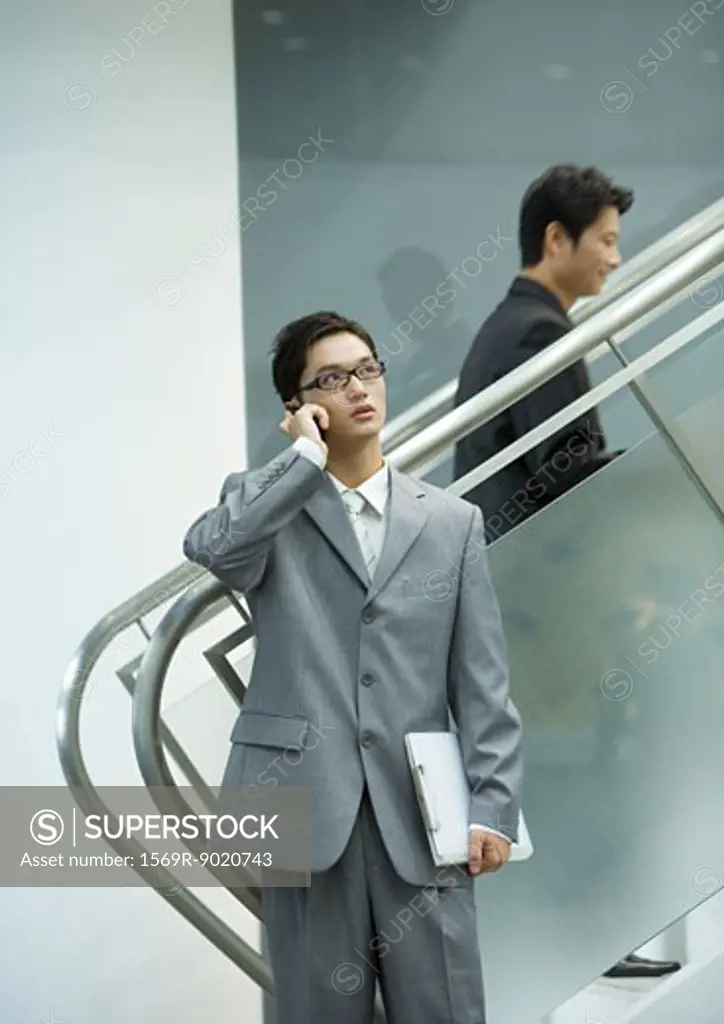 Businessman using cell phone near staircase