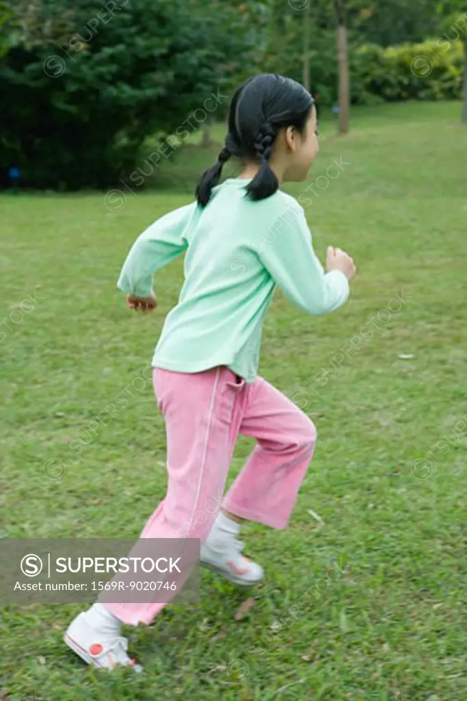 Little girl running across grass