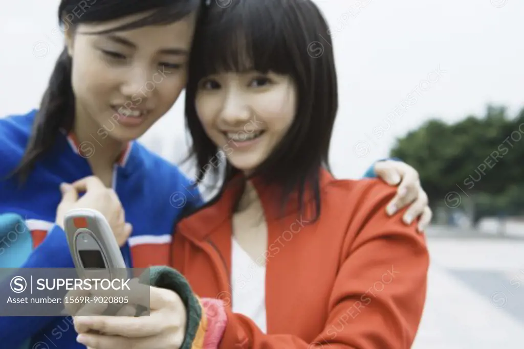Two young women friends looking at cell phone together