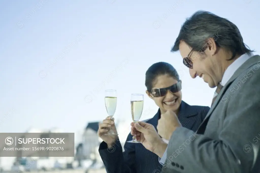 Business partners holding up glasses of champagne, skyline in background