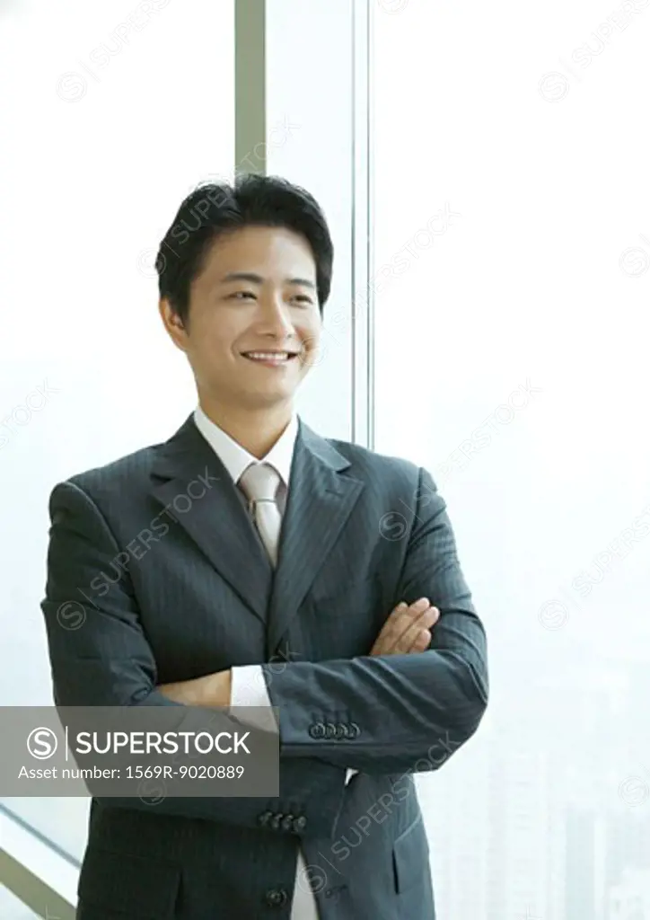 Businessman standing with arms folded, smiling