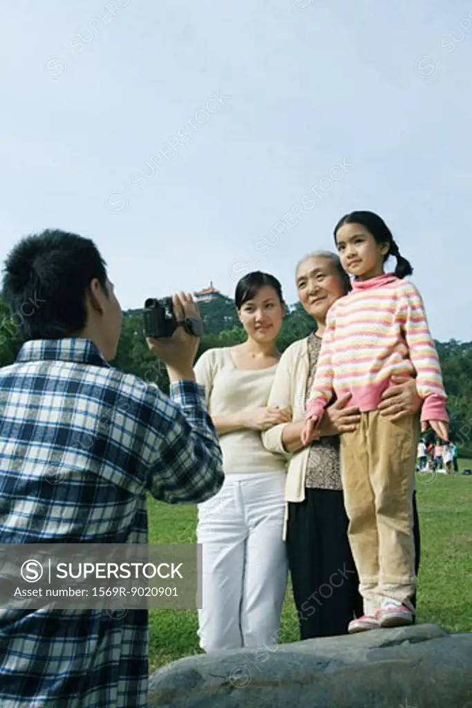Man filming family in park with video camera