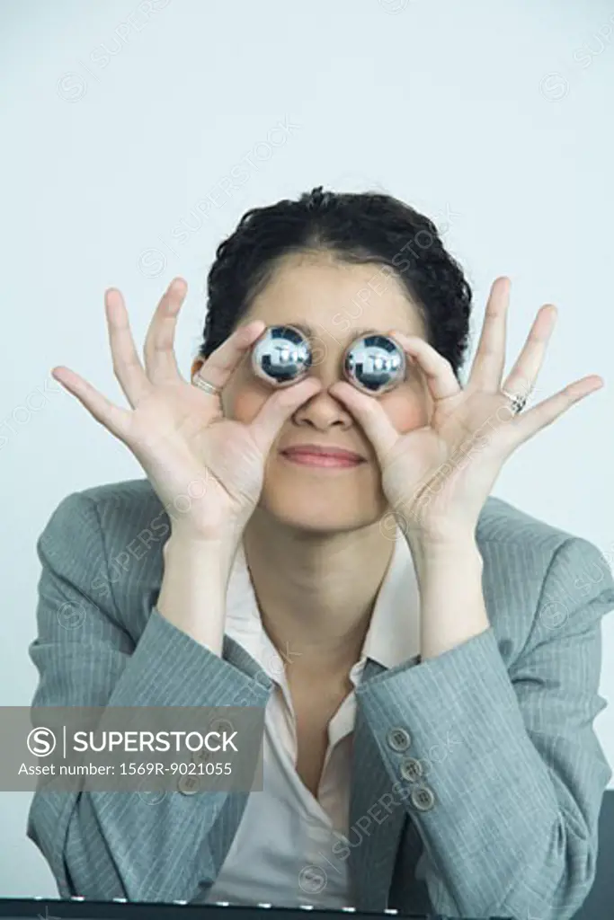 Businesswoman holding yinyang balls, in front of eyes