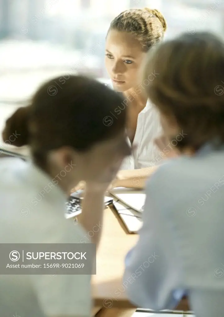 Young couple sitting across table from young female professional, woman whispering to man