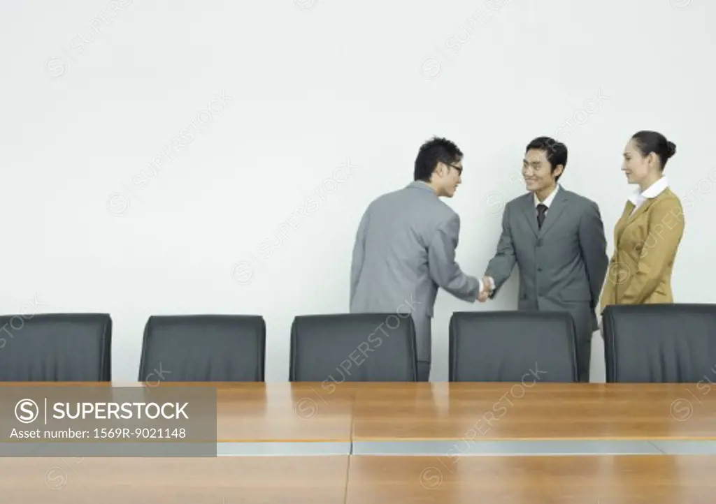 Business associates shaking hands in conference room
