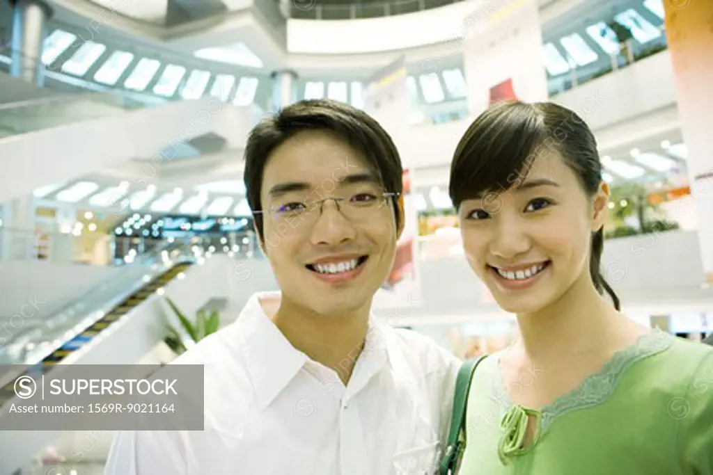 Couple in shopping mall, smiling at camera, portrait