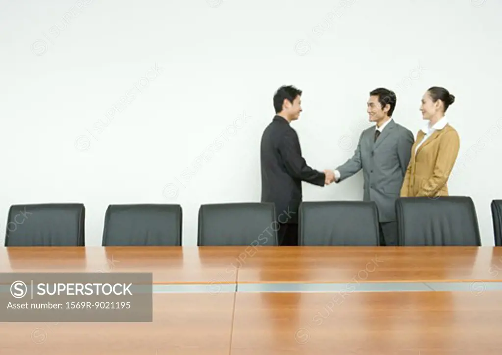 Business associates shaking hands in conference room