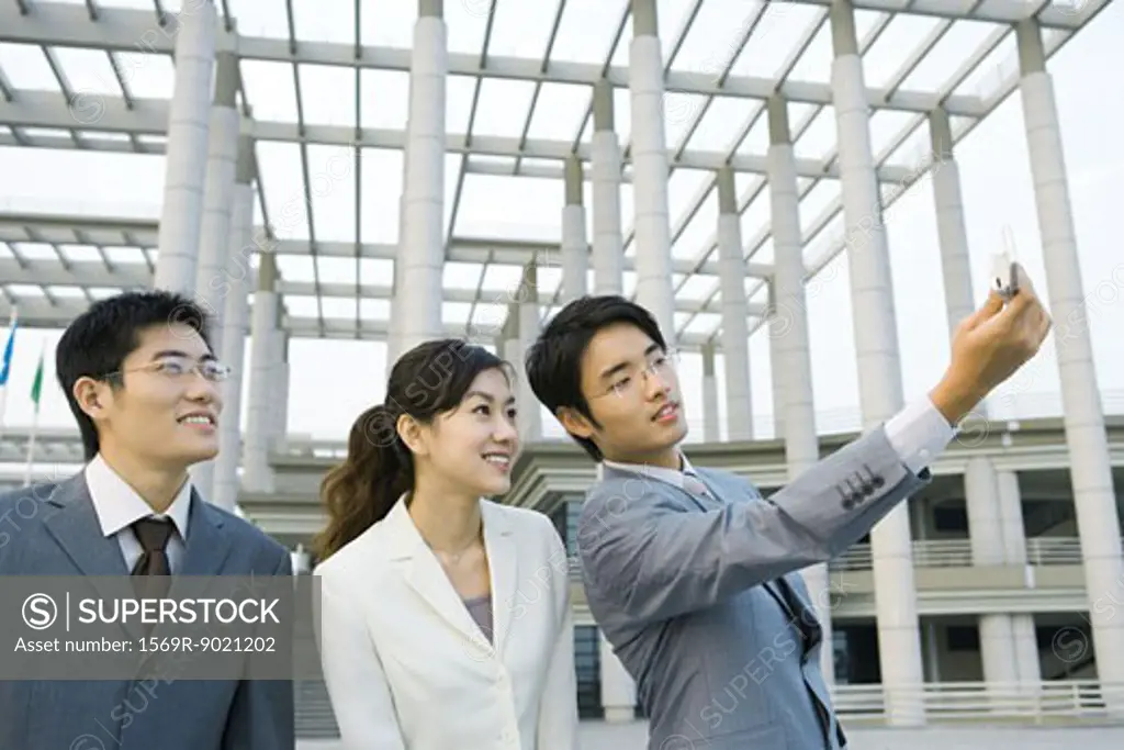 Businessman taking photo of self and two colleagues with cell phone