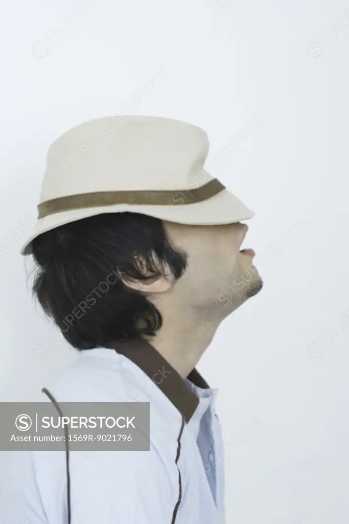 Young man wearing hat pulled down over eyes, side view