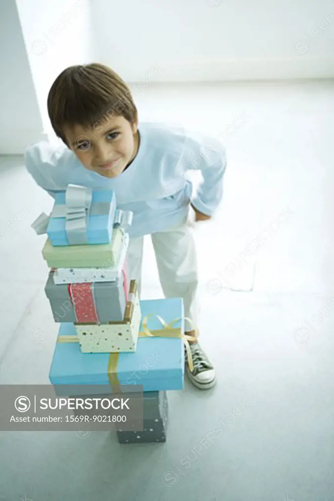 Boy standing next to stack of Christmas presents