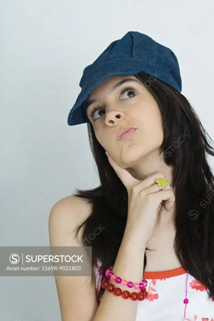 Teenage girl with finger on cheek, looking up, portrait