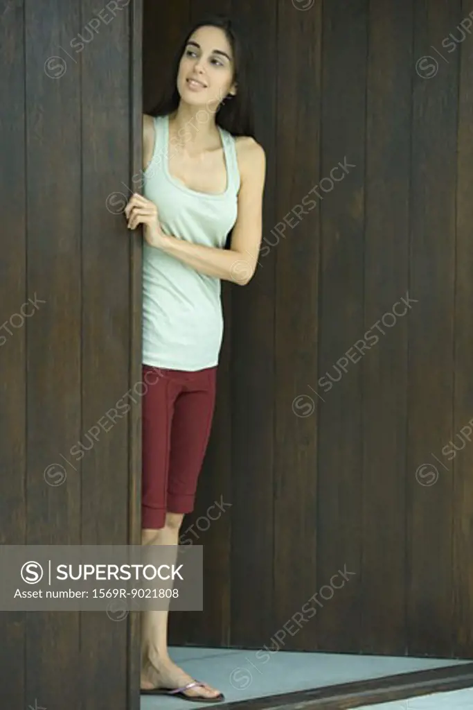 Woman looking out of doorway, full length