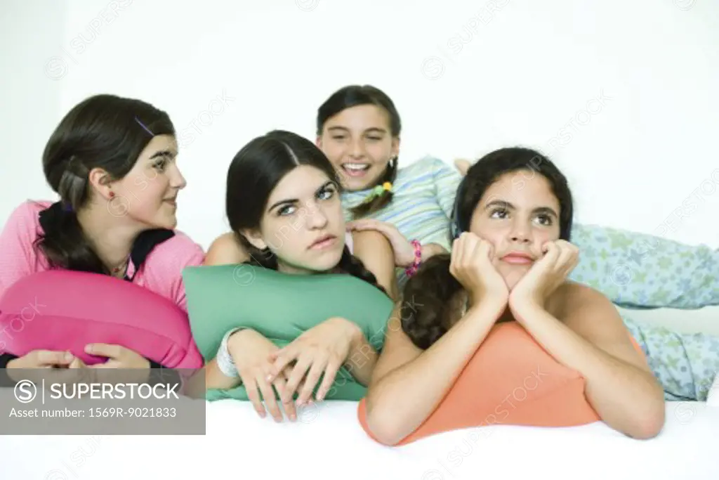 Four young female friends reclining with cushions and looking away