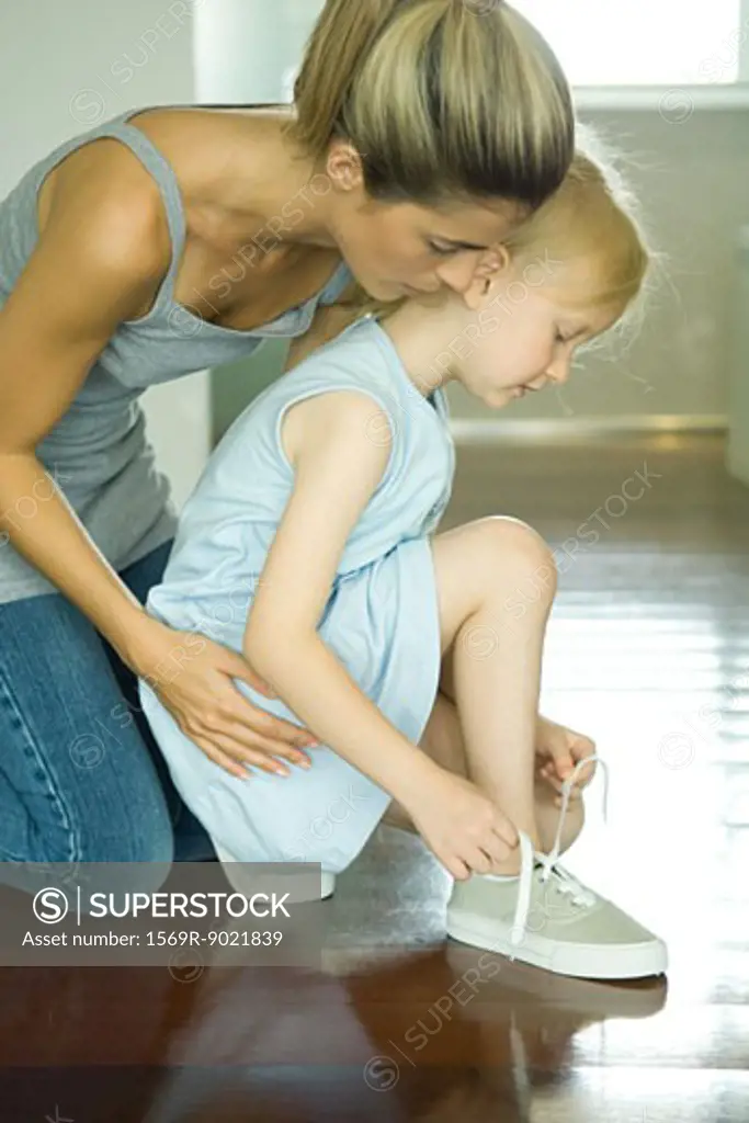 Mother watching daughter ties shoe laces