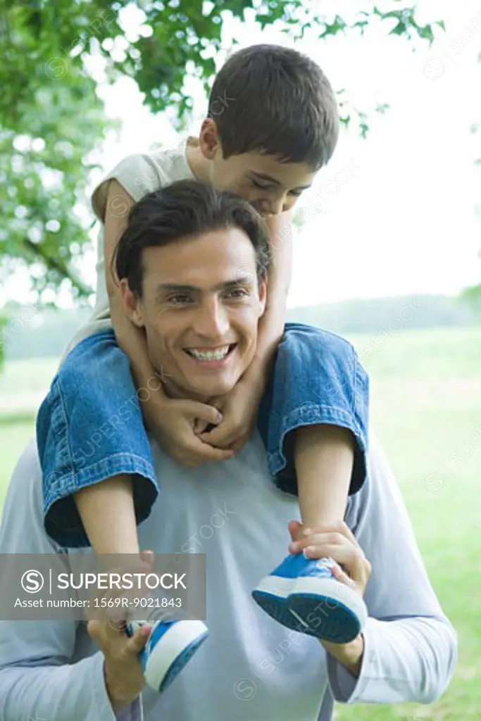 Boy riding on father's shoulders, both smiling