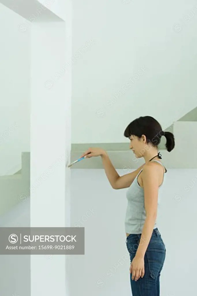 Woman painting wall with paint brush