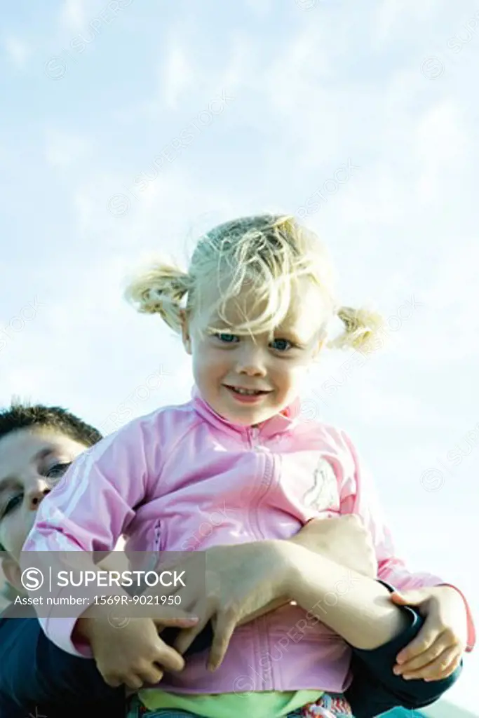 Boy holding up little girl, low angle view