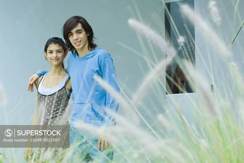 Young couple, smiling at camera, long grass in foreground