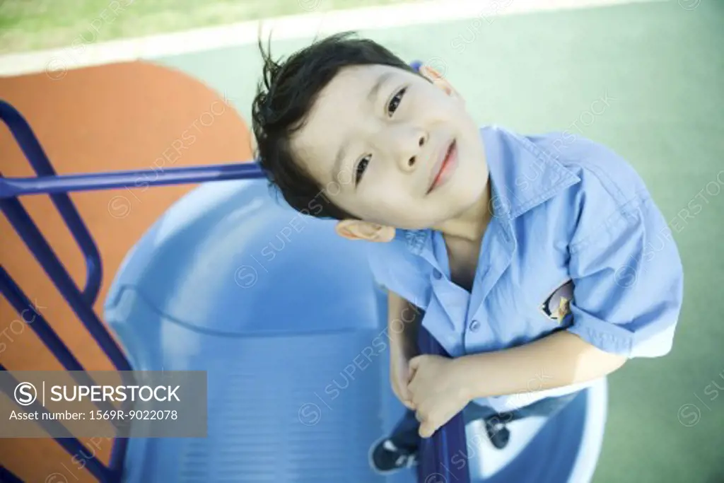 Boy on playground equipment, smiling at camera