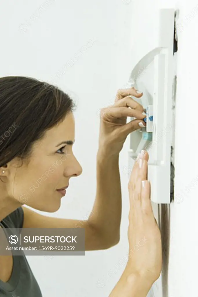 Woman replacing fuse in fusebox