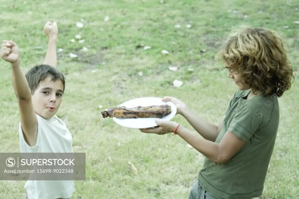 Boy handing friend plate of grilled meat