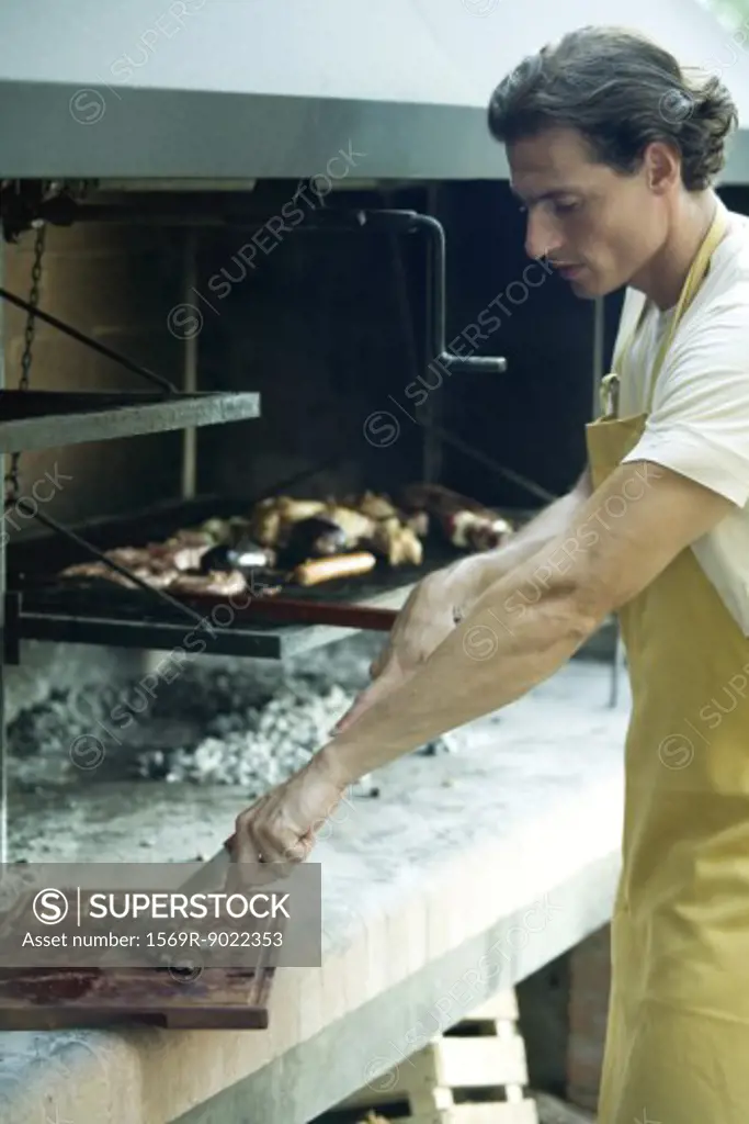 Man barbecuing, cutting piece of meat
