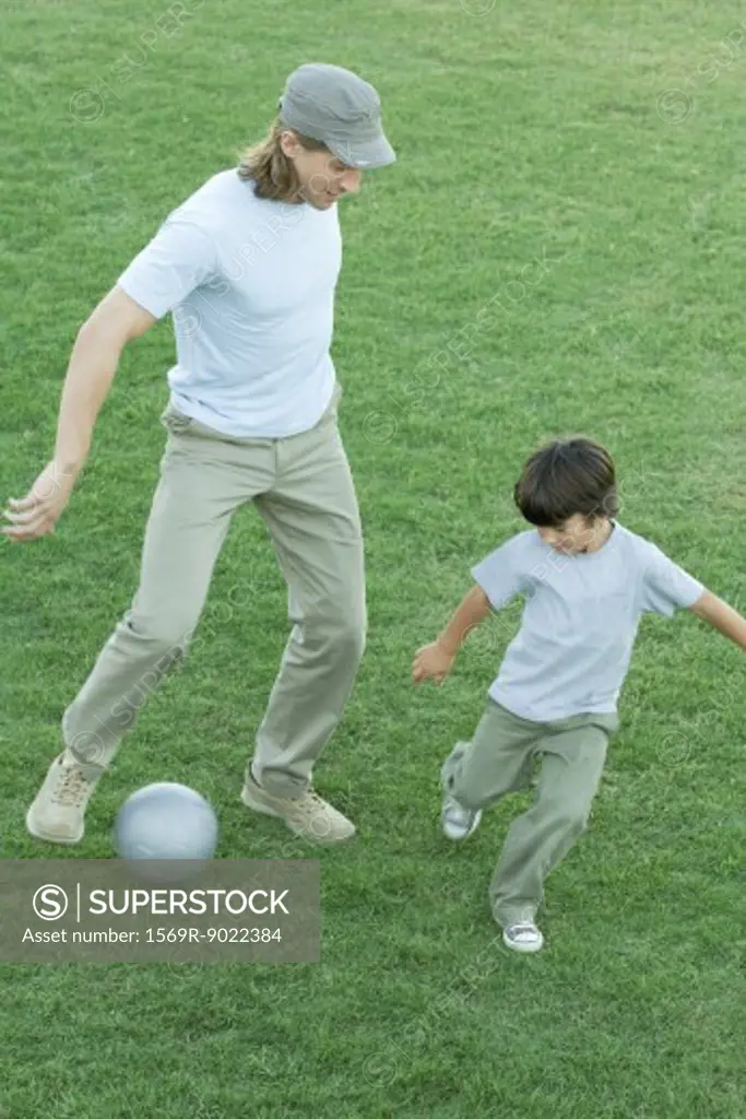 Man and boy playing soccer on grass