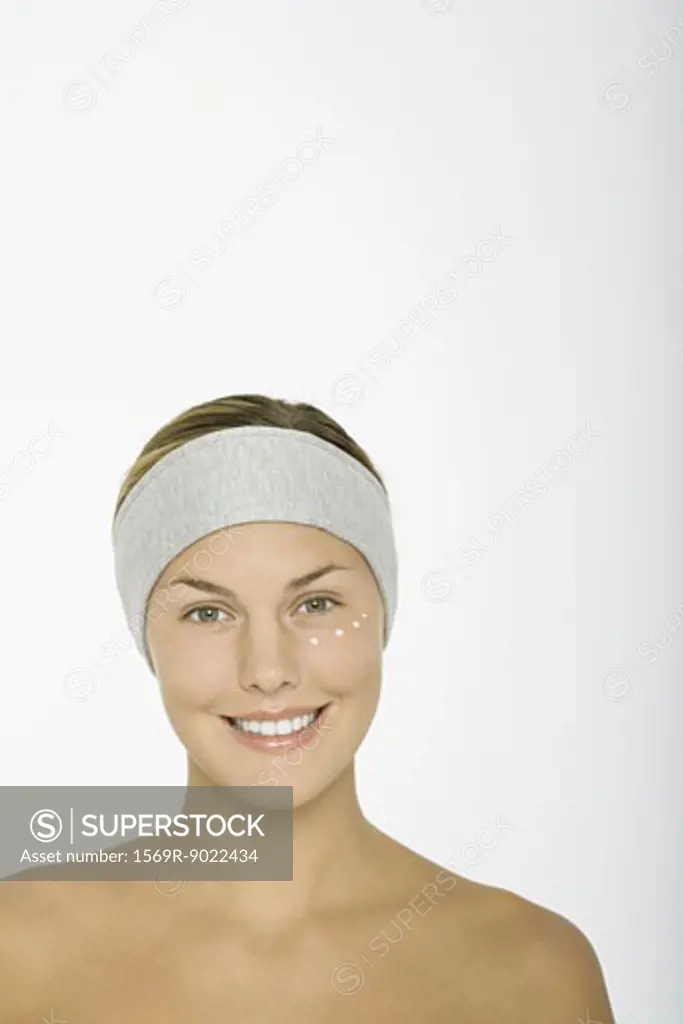 Young woman with dots of moisturizer under eye
