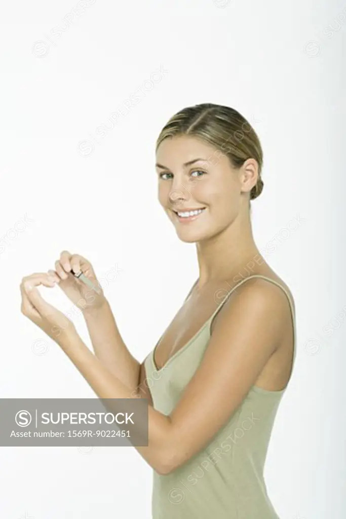Young woman filing nails, smiling at camera