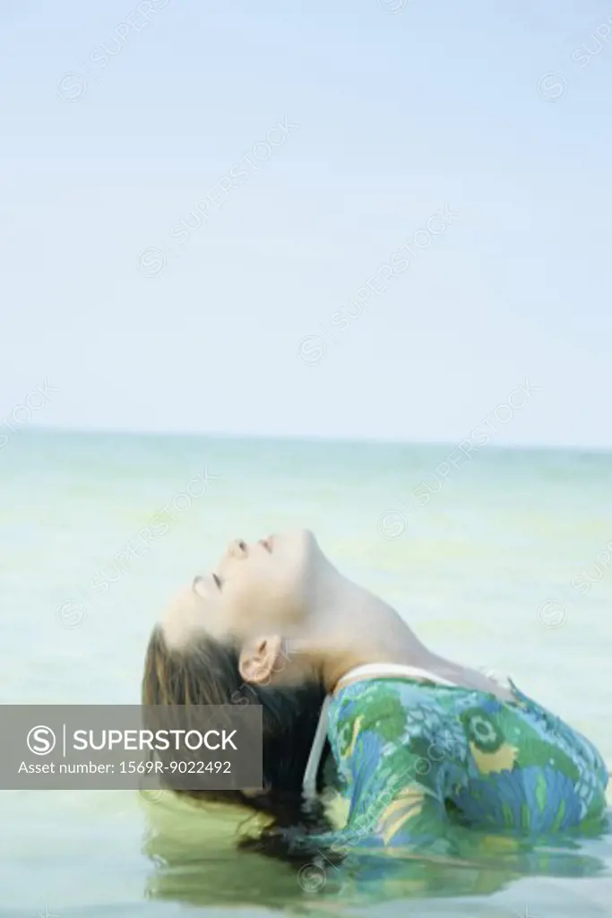 Woman in sea, bending head back 