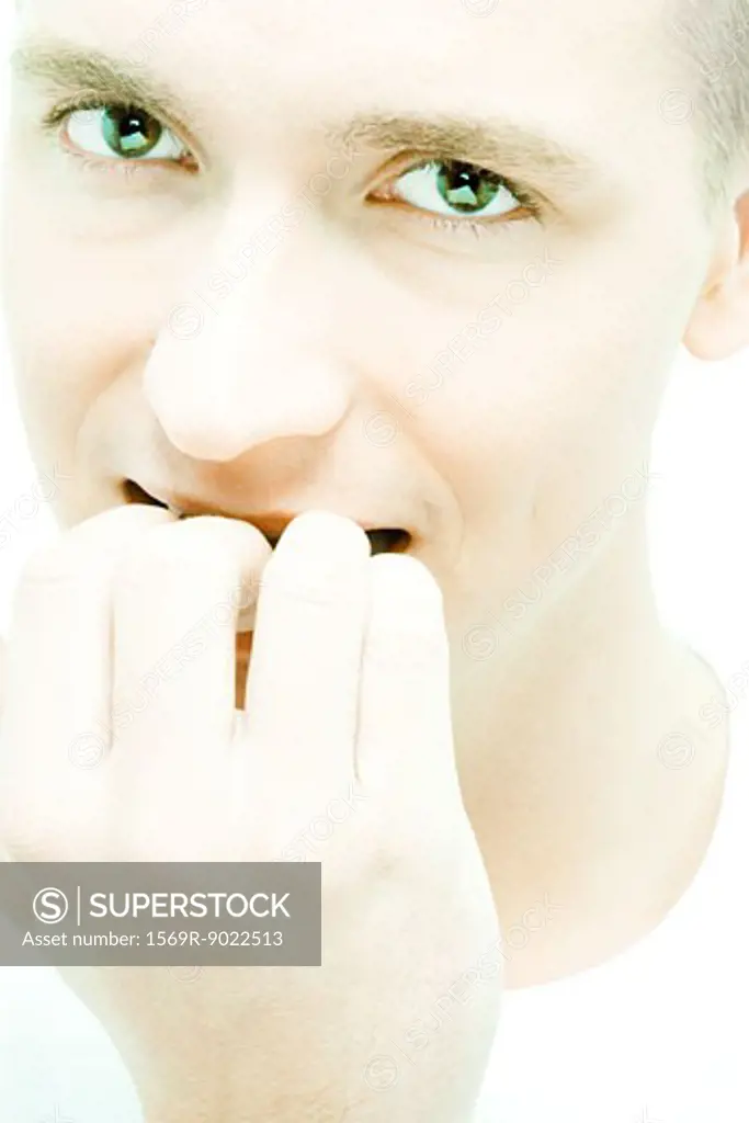 Young man biting nails, close-up