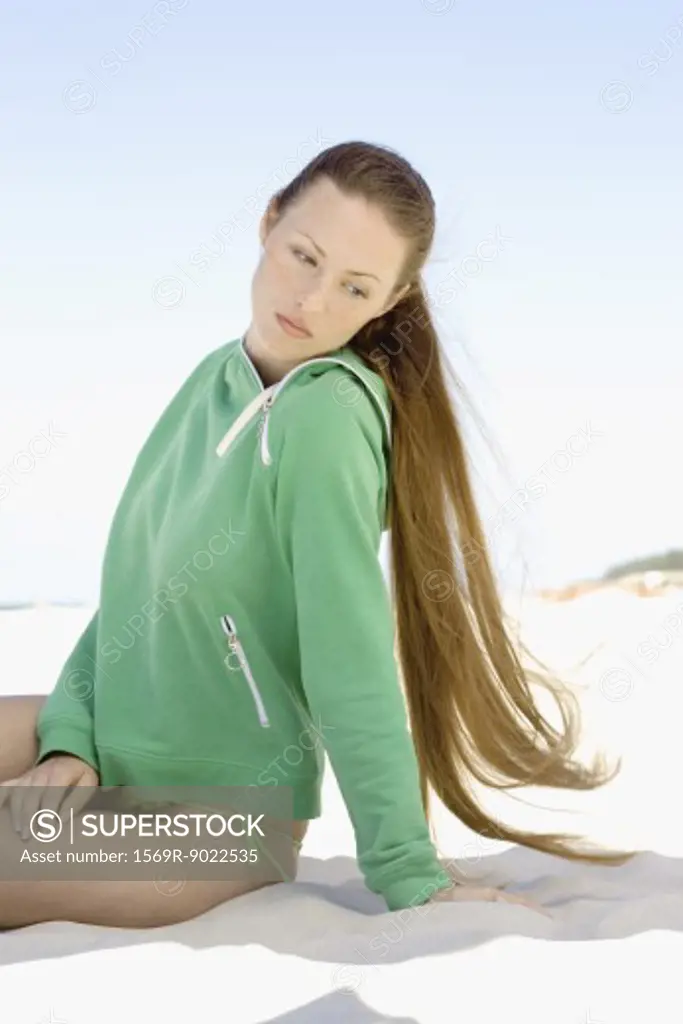 Woman with long hair sitting on sand