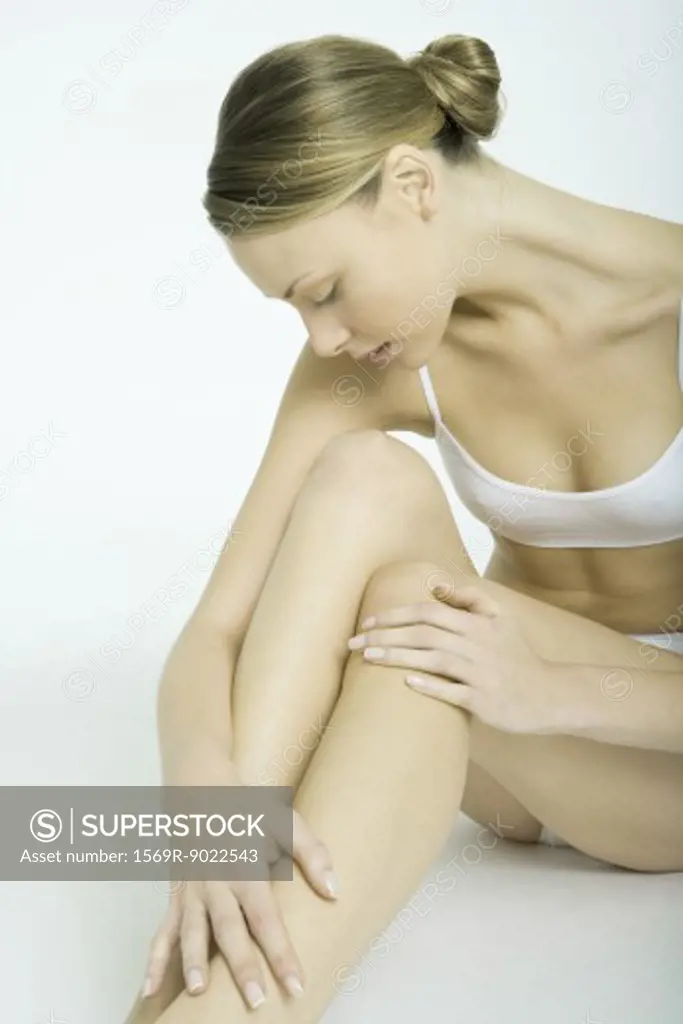 Young woman sitting in underwear, looking at legs