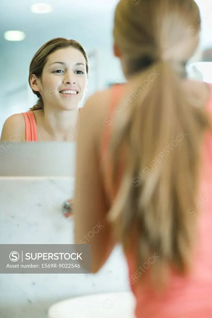 Young woman looking at self in mirror