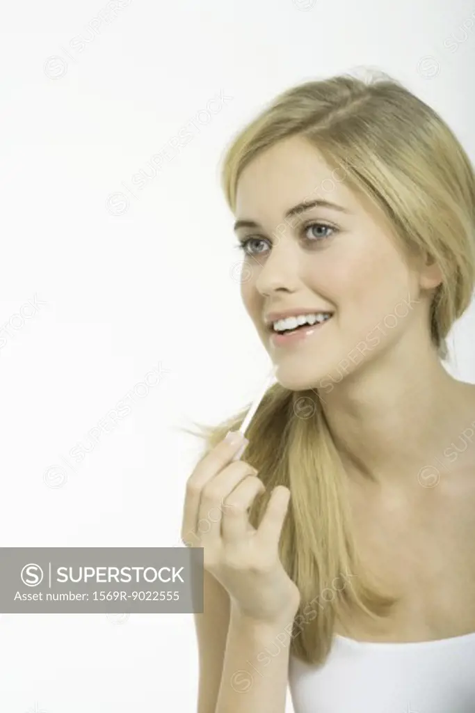 Teenage girl putting on lipgloss