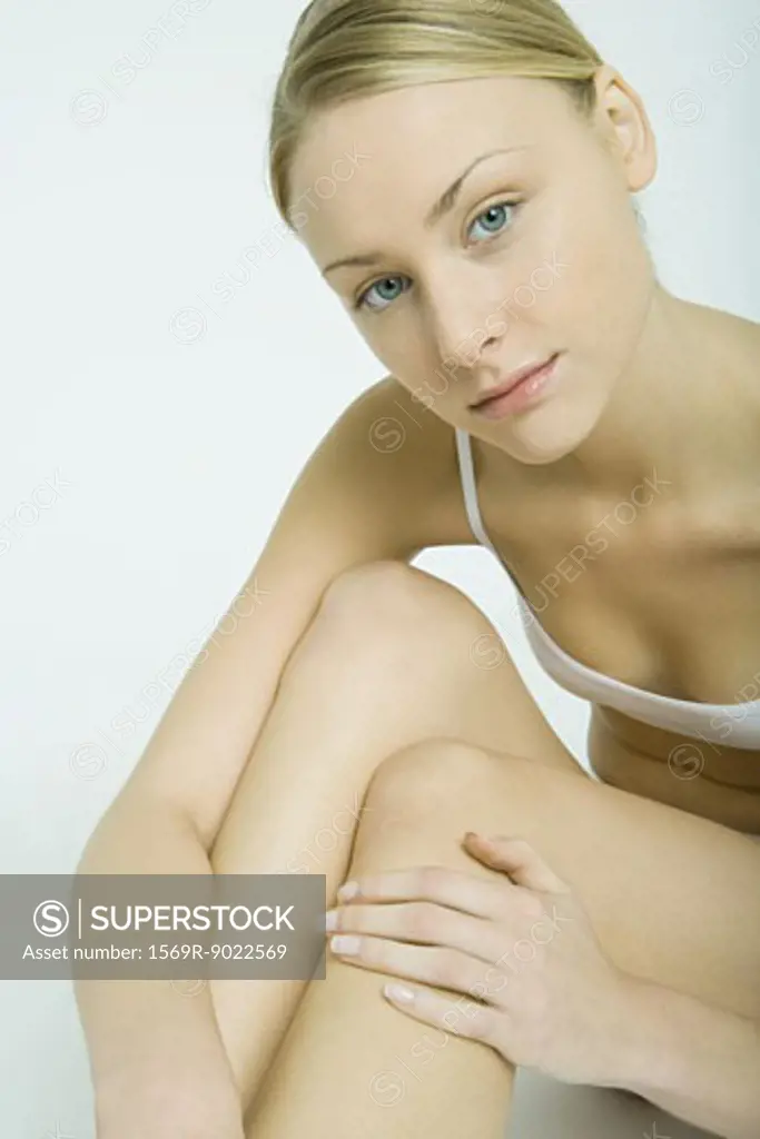 Young woman sitting in underwear, touching legs