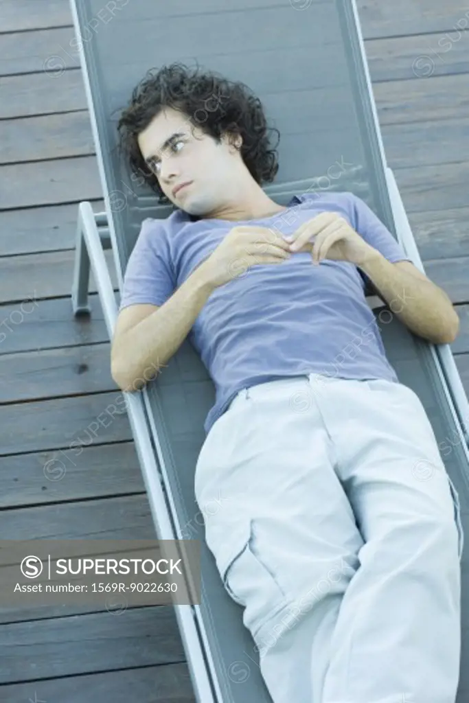 Young man lying on lounge chair