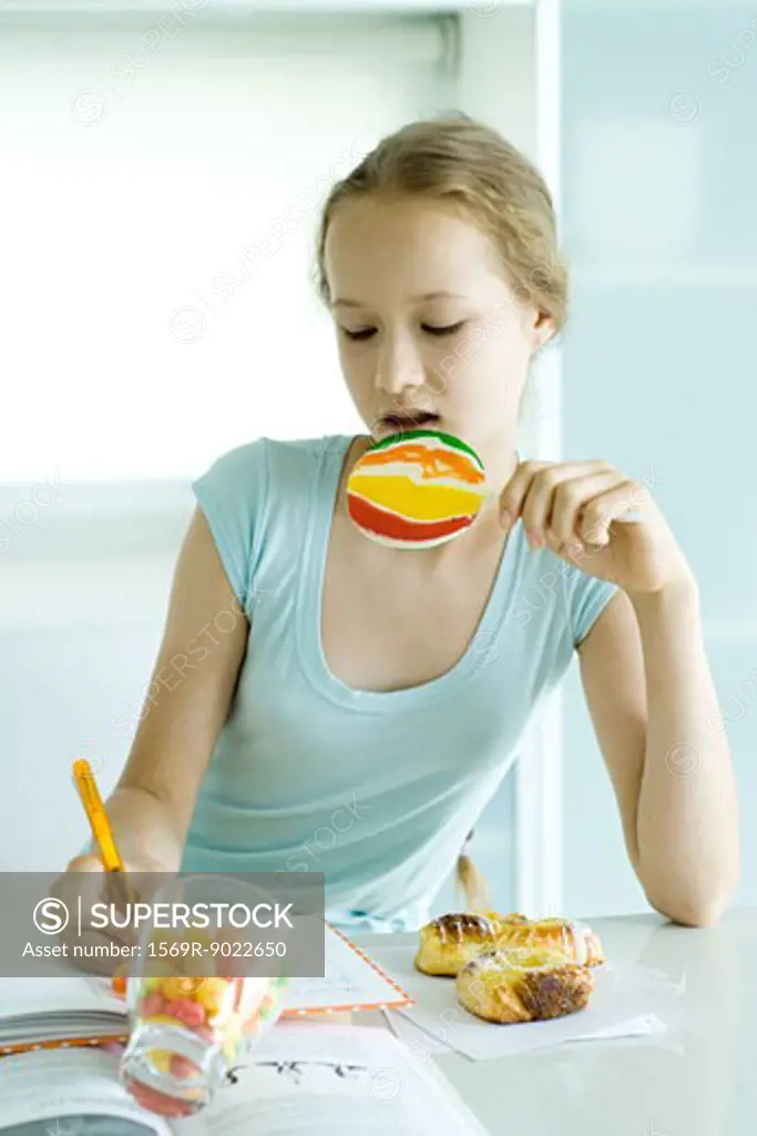 Girl doing homework and eating junk food
