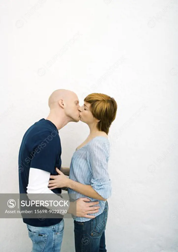 Young couple kissing, hands on each other's waists