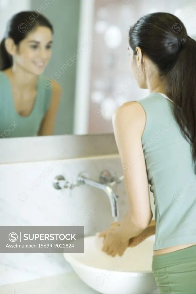 Woman washing hands in bathroom sink