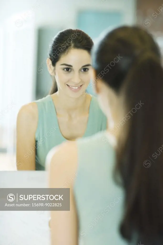 Young woman looking at self in mirror