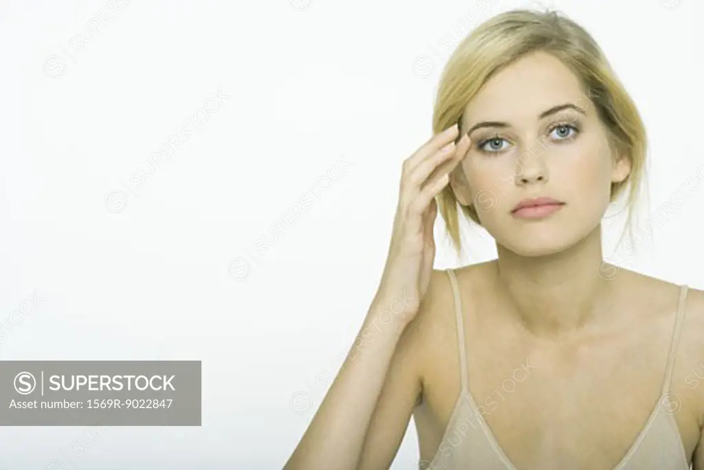Teenage girl wearing make-up, touching side of eye