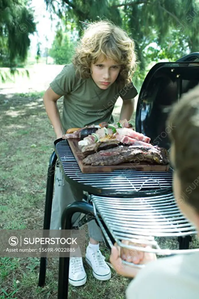 Two boys standing at either end of barbecue
