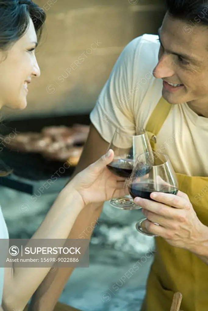 Couple having cookout and clinking wine glasses
